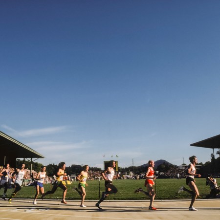 Runners competing in a track race on a sunny day, with packed grandstands. Here's why everyone should know their mile time, even if you're not a runner.
