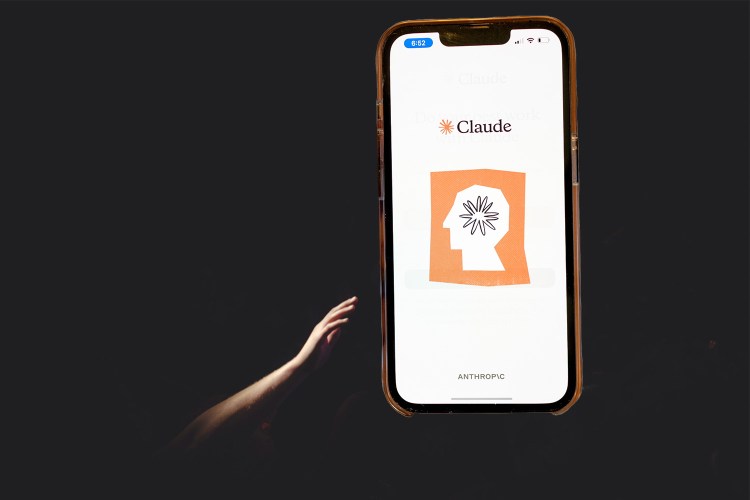 A hand reaching through darkness to a large iPhone depicting an AI logo on a backlit screen.